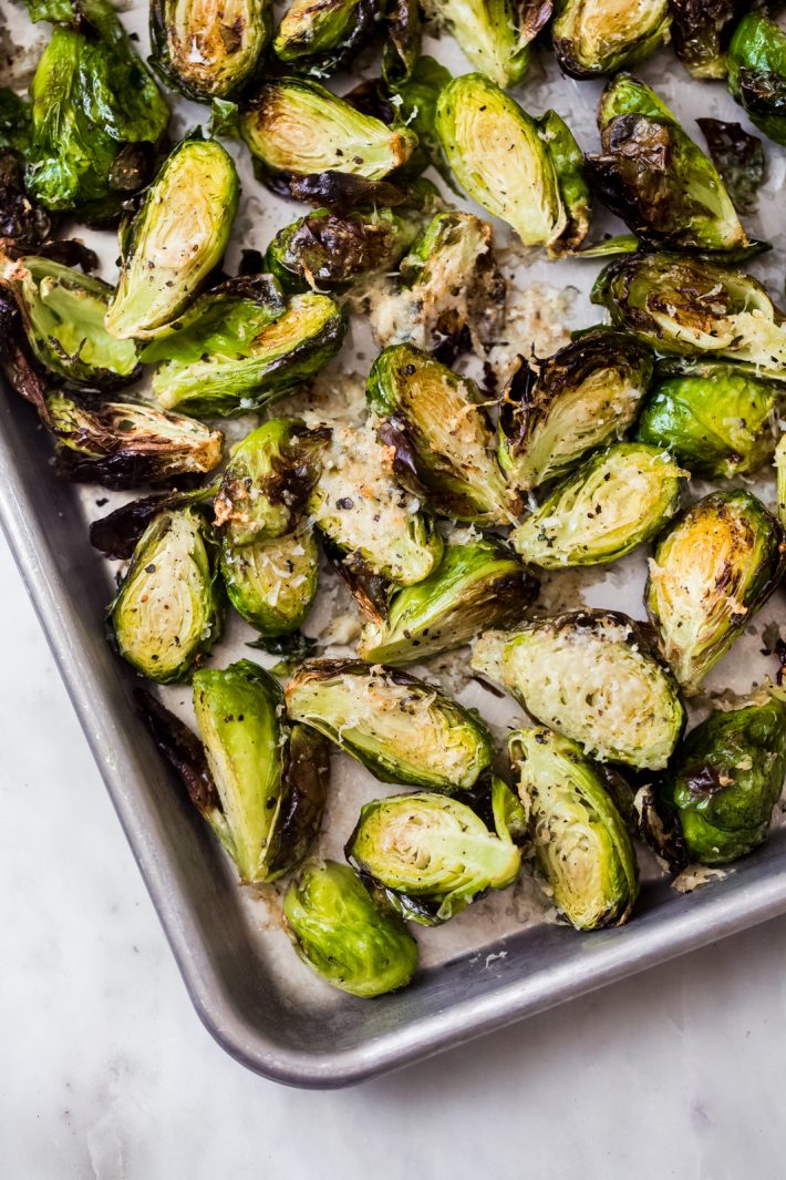 brussels sprouts topped with pecorino cheese on baking sheet